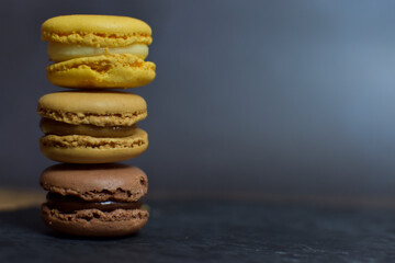 Macarons brown and yellow tones, on a slate plate with a black background.
