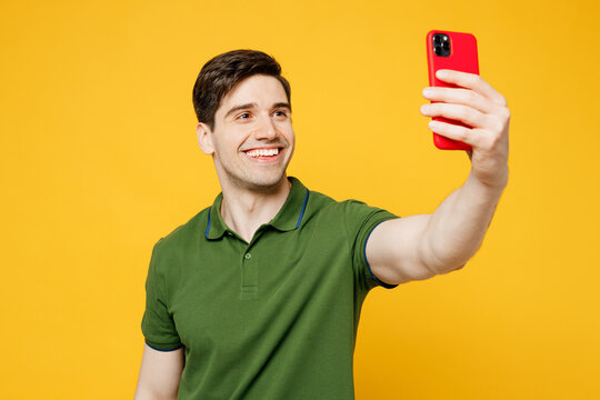 Young caucasian happy man wears green t-shirt casual clothes oing selfie shot on mobile cell phone post photo on social network isolated on plain yellow background studio portrait. Lifestyle concept.