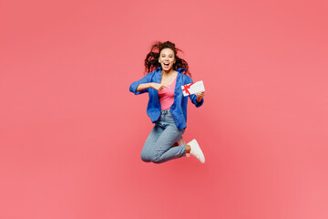 Full bocy young woman of African American ethnicity she wears blue shirt casual clothes jump high hold gift certificate coupon voucher card for store isolated on plain pastel pink background studio.