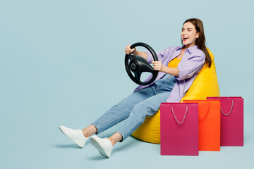 Full body young woman wears casual clothes sit in bag chair near shopping package bags hold...