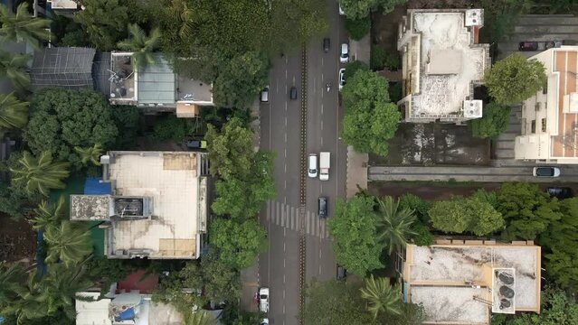 Topdown drone shot of a T intersection in suburban Mumbai, Chembur - India with light vehicular traffic and people crossing road.