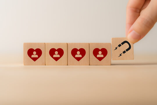 Customer engagement, increasing customer loyalty concept. Building relationships, increase brand awareness, and drive sales. Wooden cube blocks with red hearts and customer loyalty icon on background.