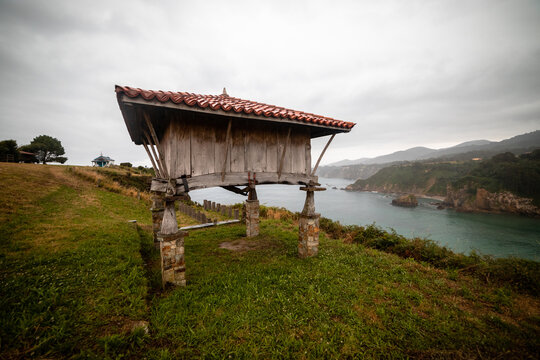 Seaside serenity framed by tradition: A coastal horreo against a backdrop of mountains and beach.