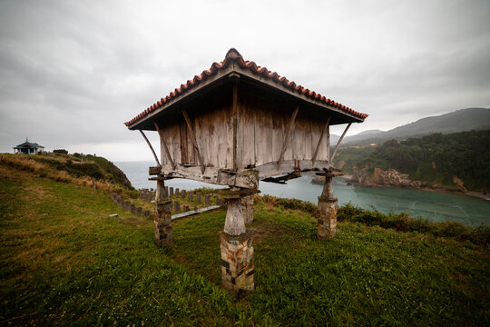 Coastal charm: Horreo overlooking beach and mountains, capturing the essence of serene beauty.