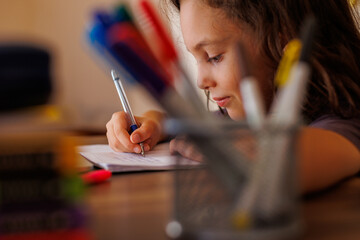 Children's hand close-up. the child uses a pencil to practice writing letters. The child learns to...