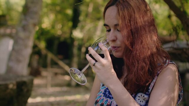 girl tastes a glass of wine in a picnic park medium shot