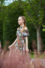 Beautiful young girl in the park. Bright green vegetation and red grass