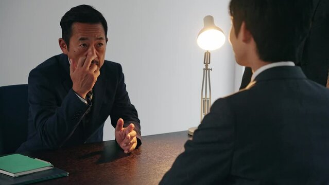 取り調べする刑事と容疑者