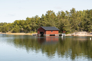Fototapeta na wymiar rotes schwedisches Bootshaus in idyllischer Lage am Wasser, Erholung in Skandinavien