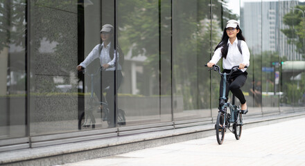 Eco friendly vehicle. 20s businesswoman ride bicycle to work in urban. Cycling has no pollution , alternative commute to global warming. Environmental preservation by sustainable energy with bicycling