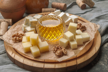 Various types of cheese with honey and nuts on wooden plate