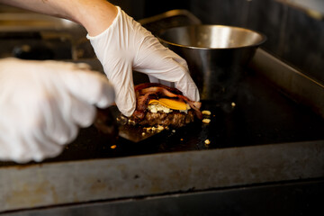 Chef cooking hamburgers, frying beef meat on pan in restaurant kitchen. Fast food restaurant worker preparing pork cutlets