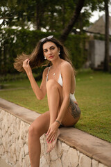 Outdoor summer  fashion photo of elegant seductive woman with wavy hairs posing on  tropical beach...