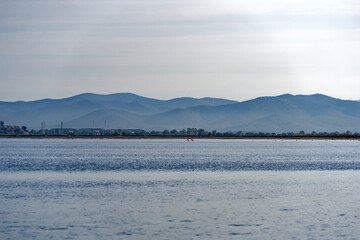 Sand beach in bright sunlight with mountain panorama in the background at Giens peninsula on a sunny spring day. Photo taken June 8th, 2023, Giens, Hyères, France.