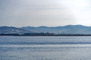 Sand beach in bright sunlight with mountain panorama in the background at Giens peninsula on a sunny spring day. Photo taken June 8th, 2023, Giens, Hy&egrave;res, France.