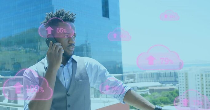 Animation of cloud icons, arrow up, percent signs over african american businessman talking on phone