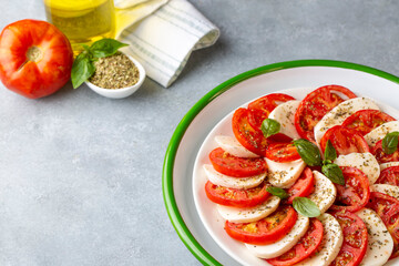 Italian caprese salad with sliced tomatoes, mozzarella, basil, olive oil
