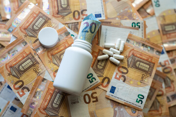 White jar with pills close-up on the background of the euro currency.