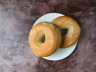Two plain bagels on a white plate atop a red mottled countertop top view - 641663720