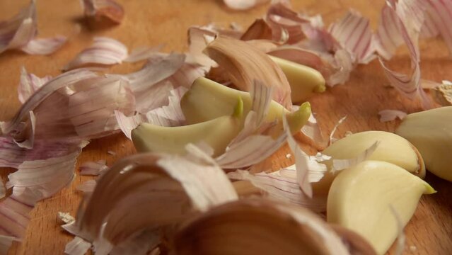 Peeled garlic cloves fall on the table along with the husk