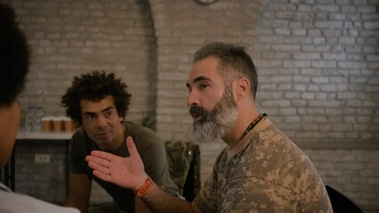 Group of diverse veterans talking during PTSD support group.