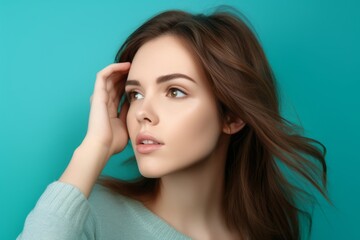 Fototapeta premium Lifestyle portrait photography of a tender girl in her 20s covering his ears against a turquoise blue background. With generative AI technology