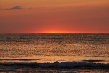 The glowing sun sinking on the horizon of the sea or ocean