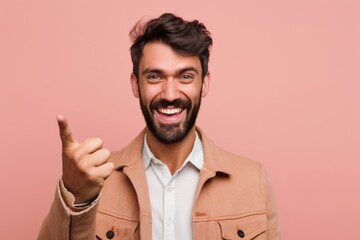 Obraz premium Headshot portrait photography of a glad boy in his 30s pointing with two hands and fingers to the side against a peachy pink background. With generative AI technology
