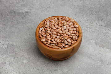 Uncooked kidney bean in wooden bowl grey stone background. 