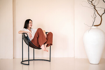 Happy woman in homewear sitting on black metal chair