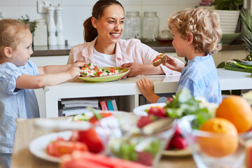 Happy woman with children eating bruschetta at home