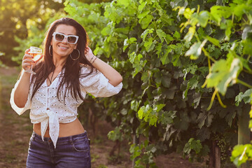 Young beautiful Smiling  italian woman walking at wineyard with a Glass of Red wine.Wine tourism at Tuscany,Italy