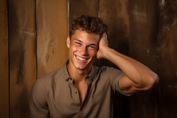 Lifestyle portrait photography of a grinning boy in his 20s holding the hand on the forehead in a headache gesture against a rustic brown background. With generative AI technology
