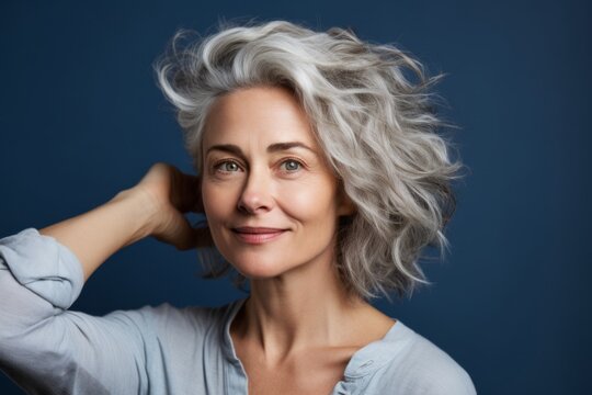 Headshot portrait photography of a glad mature woman touching her hair against a soft blue background. With generative AI technology