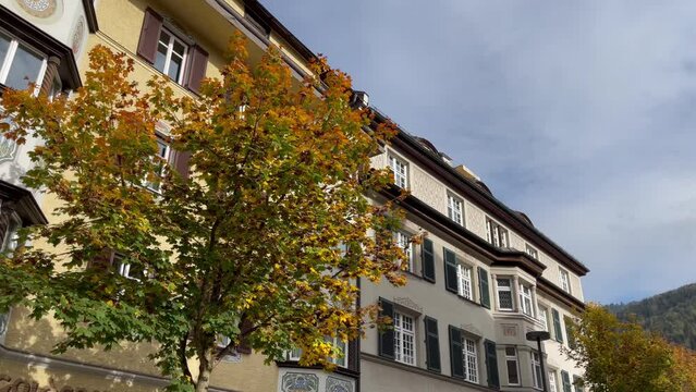 Kufstein town buildings with brown leaves trees on walking tour. European old city architecture in autumn season, travel destination concepts