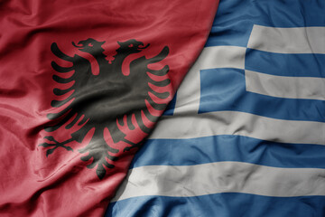 big waving national colorful flag of albania and national flag of greece .