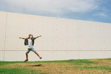 Naklejka premium Carefree boy jumping against wall