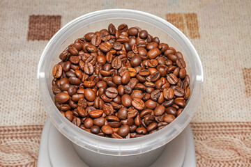 Roasted coffee beans in a plastic container (small bucket) close-up top view