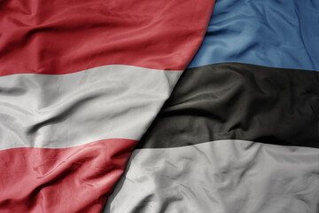 big waving national colorful flag of austria and national flag of estonia .