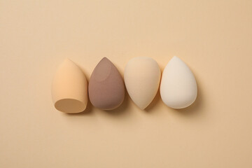 Cosmetic sponges on beige background, top view