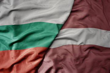 Fototapeta premium big waving national colorful flag of bulgaria and national flag of latvia .