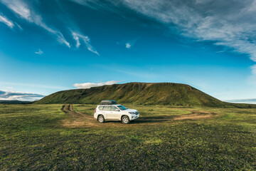4wd car parked on remote wilderness and mossy hill in summer at Icelandic Highlands - obrazy, fototapety, plakaty