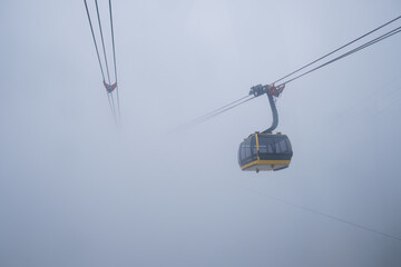 Cable car carries passenger moving on the mountain among the foggy in cloudy day at Sapa