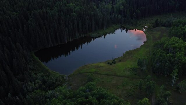 Drone shot of the mirror-like surface of the lake beautifully reflects the vivid red clouds above