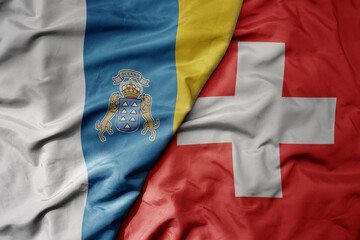 Fototapeta premium big waving national colorful flag of canary islands and national flag of switzerland .