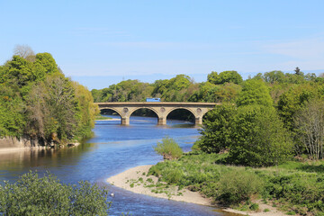 Fototapeta na wymiar A bright sunny view in spring across the River Tweed from Scotland towards England.