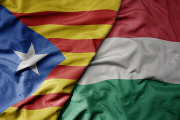 big waving national colorful flag of catalonia and national flag of hungary .