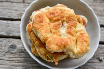 Traditional Bulgarian home made deep fried  patties  covered with sugar  оn rustic backgroud.Mekitsa or Mekica,  on wooden  rustic  background. Made of kneaded dough that is deep fried 