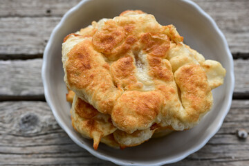 Traditional Bulgarian home made deep fried  patties  covered with sugar  оn rustic backgroud.Mekitsa or Mekica,  on wooden  rustic  background. Made of kneaded dough that is deep fried 
