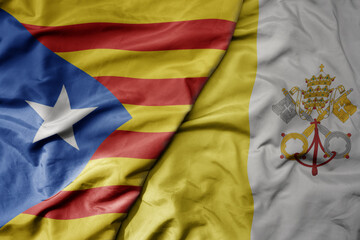 big waving national colorful flag of catalonia and national flag of vatican city .